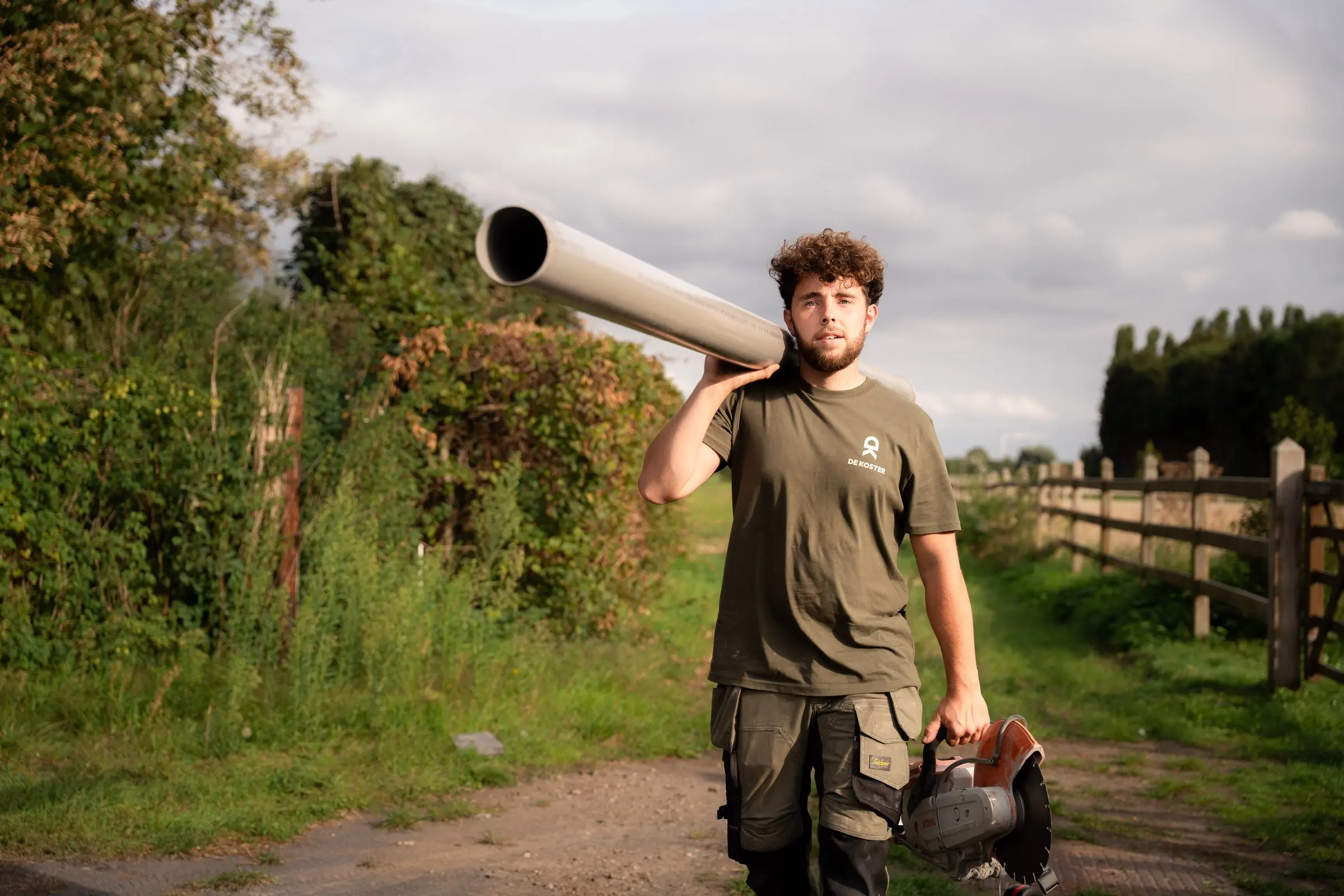 Jaro draagt een drainagebuis over het terrein