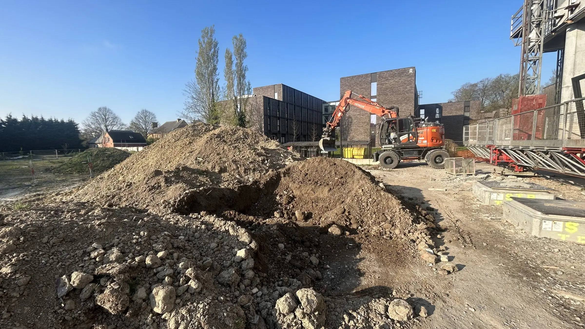 Grondberg en kraan op de werf, gezien vanaf de aanleg