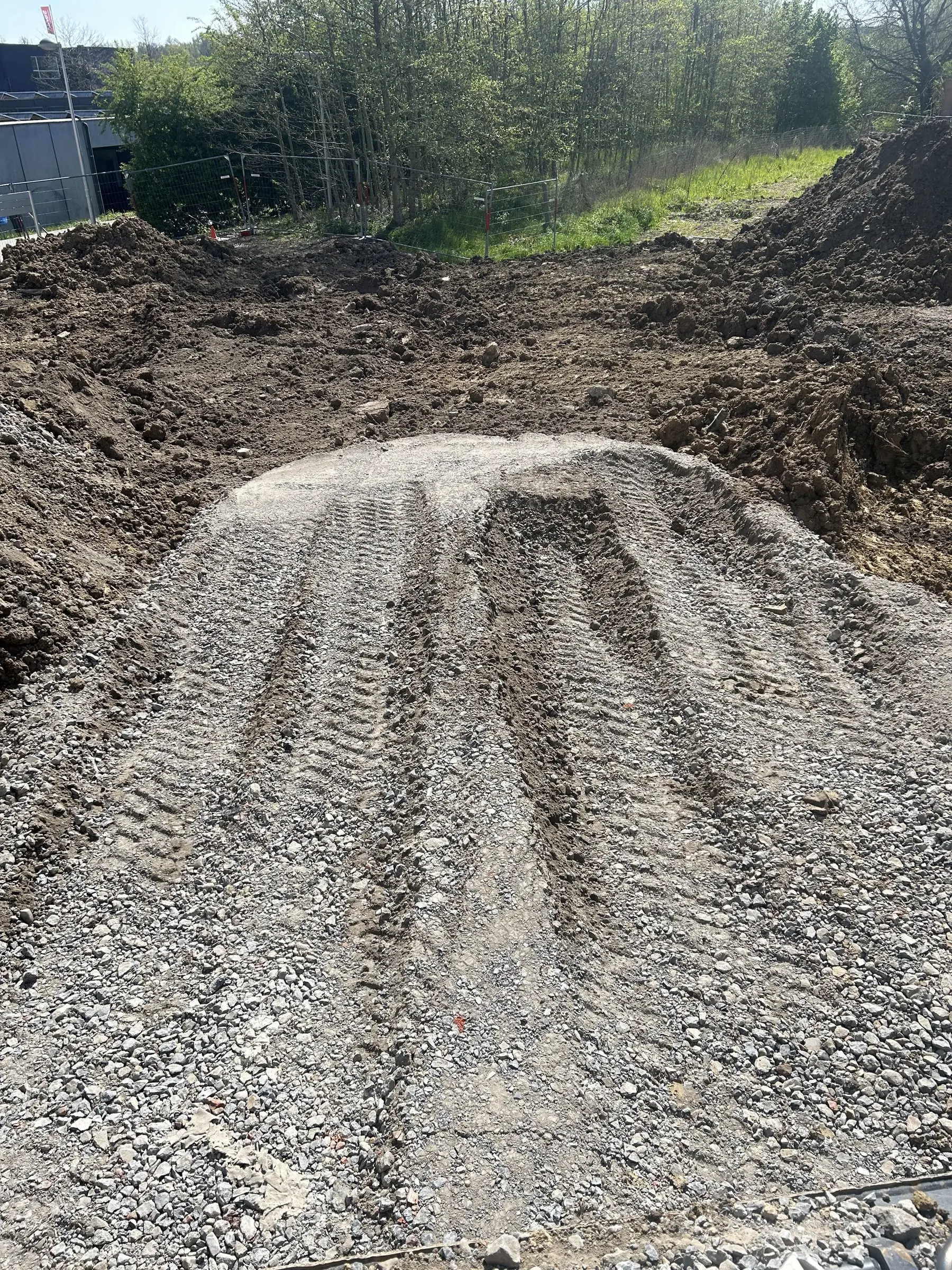 Verdichte steenslag met bandensporen naast het uitgegraven terrein