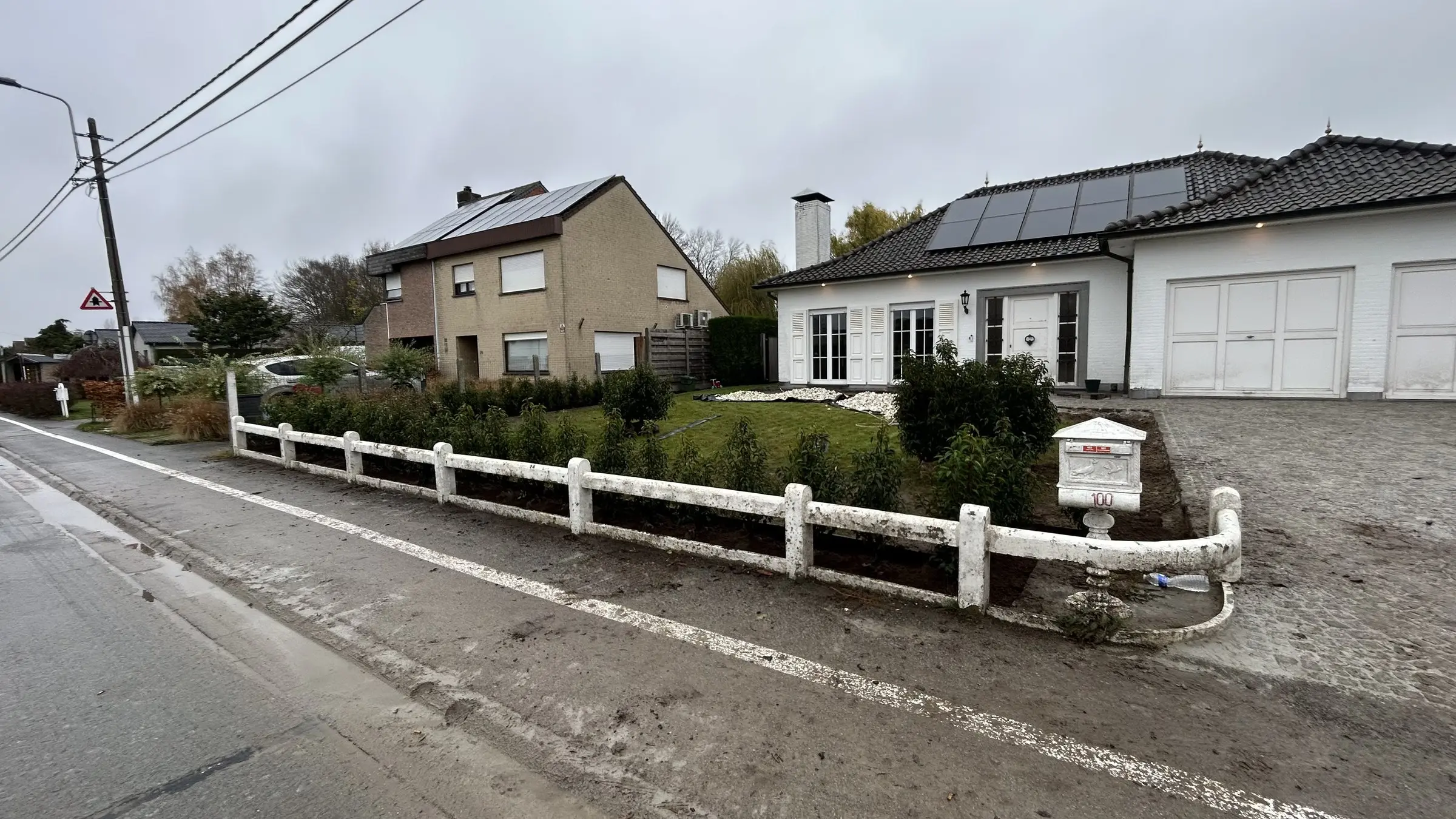 Nieuwe haagbeplanting achter een wit hekwerk aan de straat