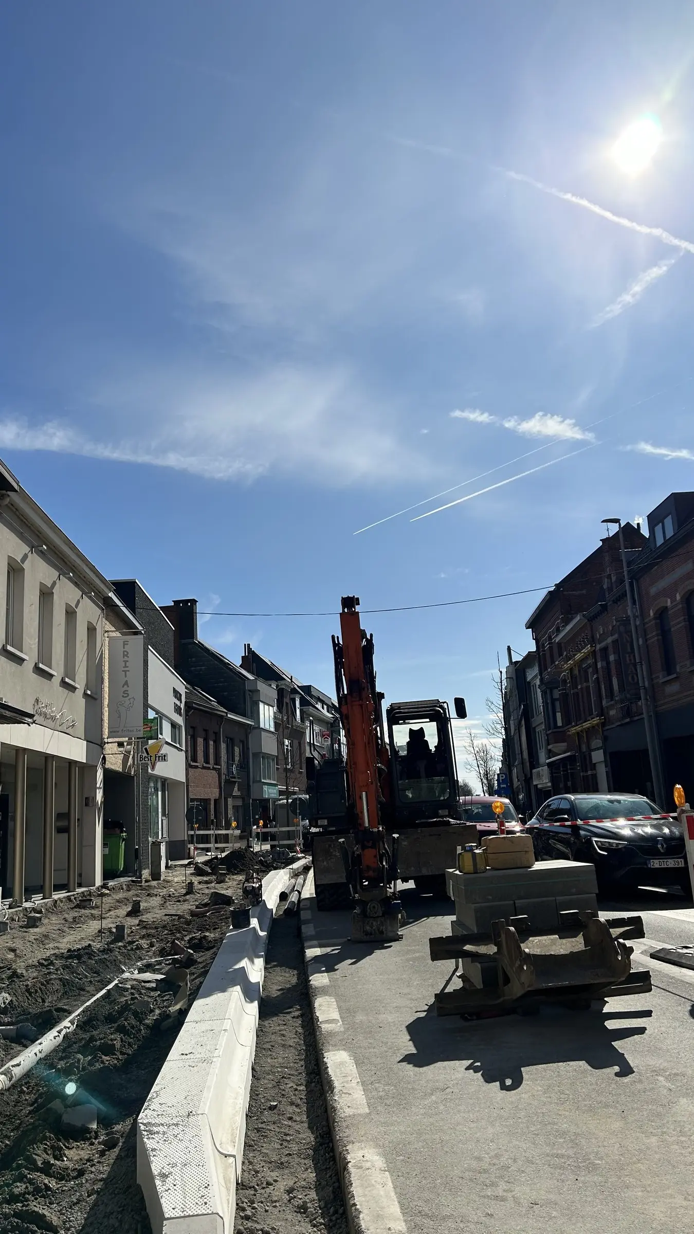 Graafmachine aan het werk in een smalle dorpsstraat