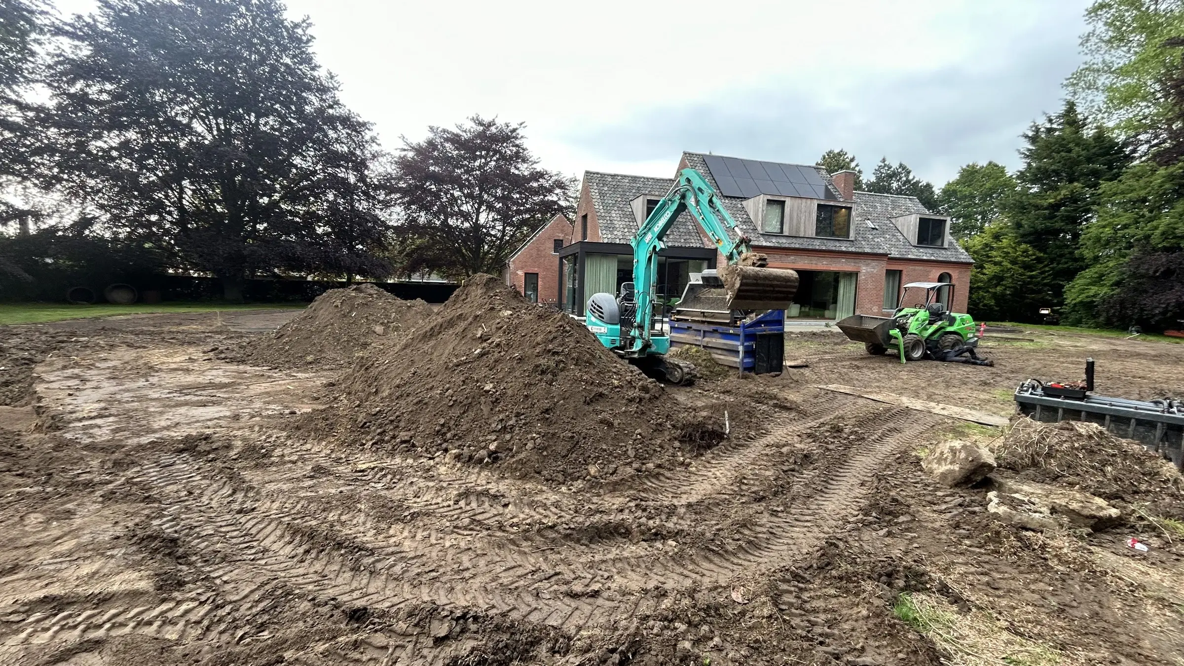 Grondberg en minigraver op het open terrein voor de villa