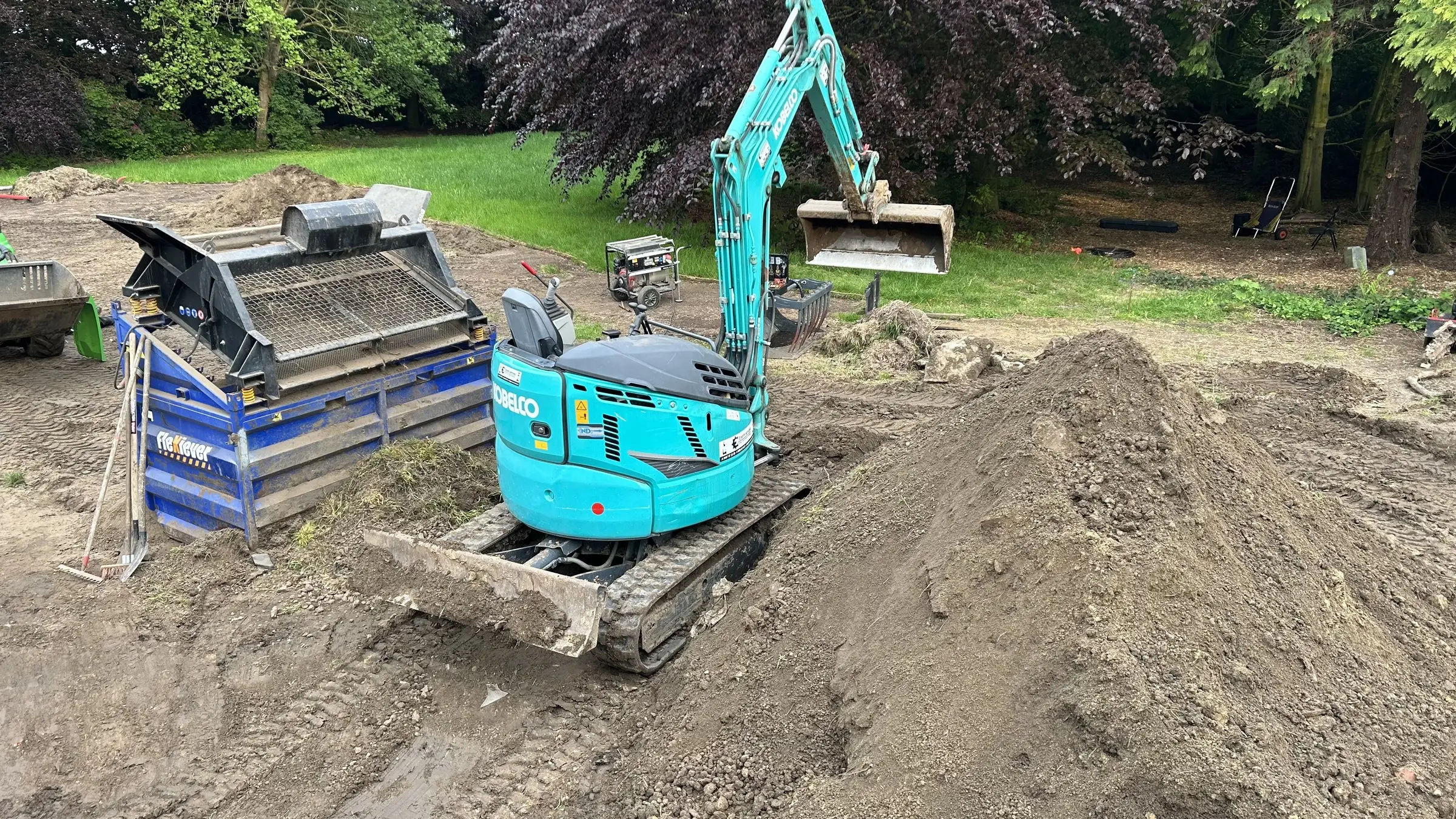 Minigraver en zeefmachine bij een grondberg