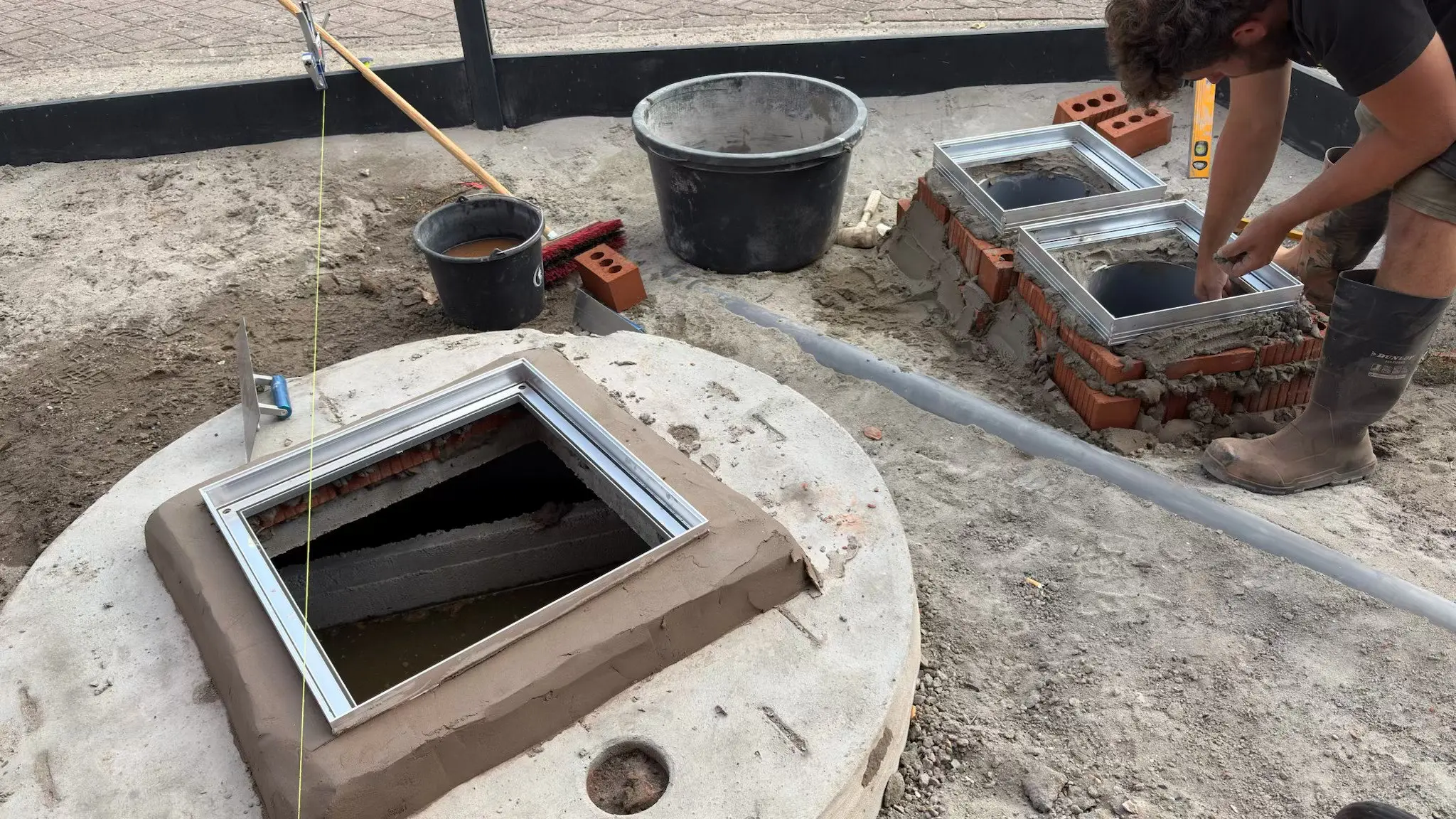 Regenput met afgewerkte rand en metselwerk voor de controleputten