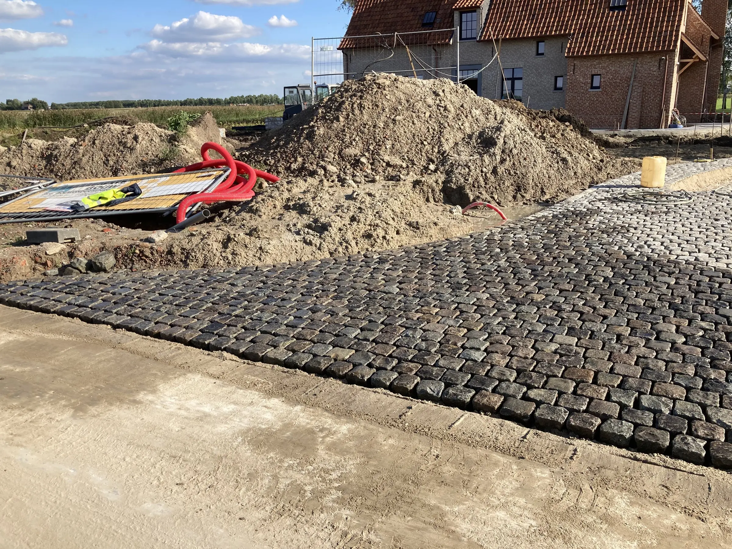 Kasseien worden gelegd langs de weg naast een hoop grond