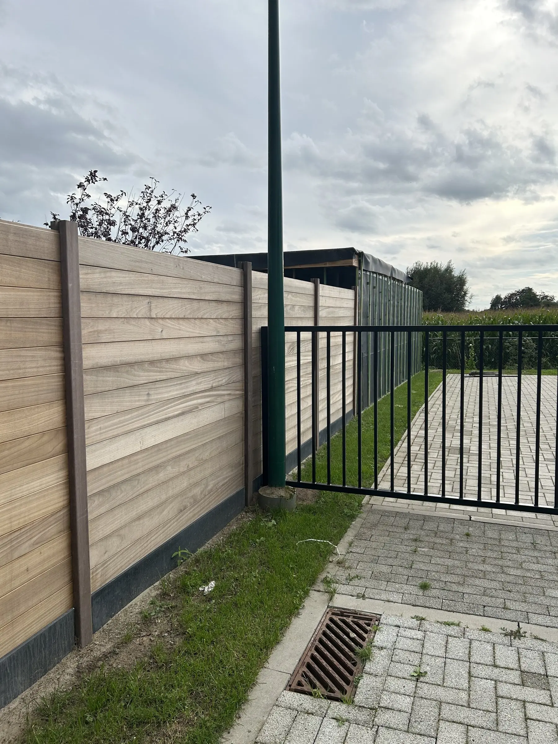 Houten afsluiting met poort langs de opritstraat