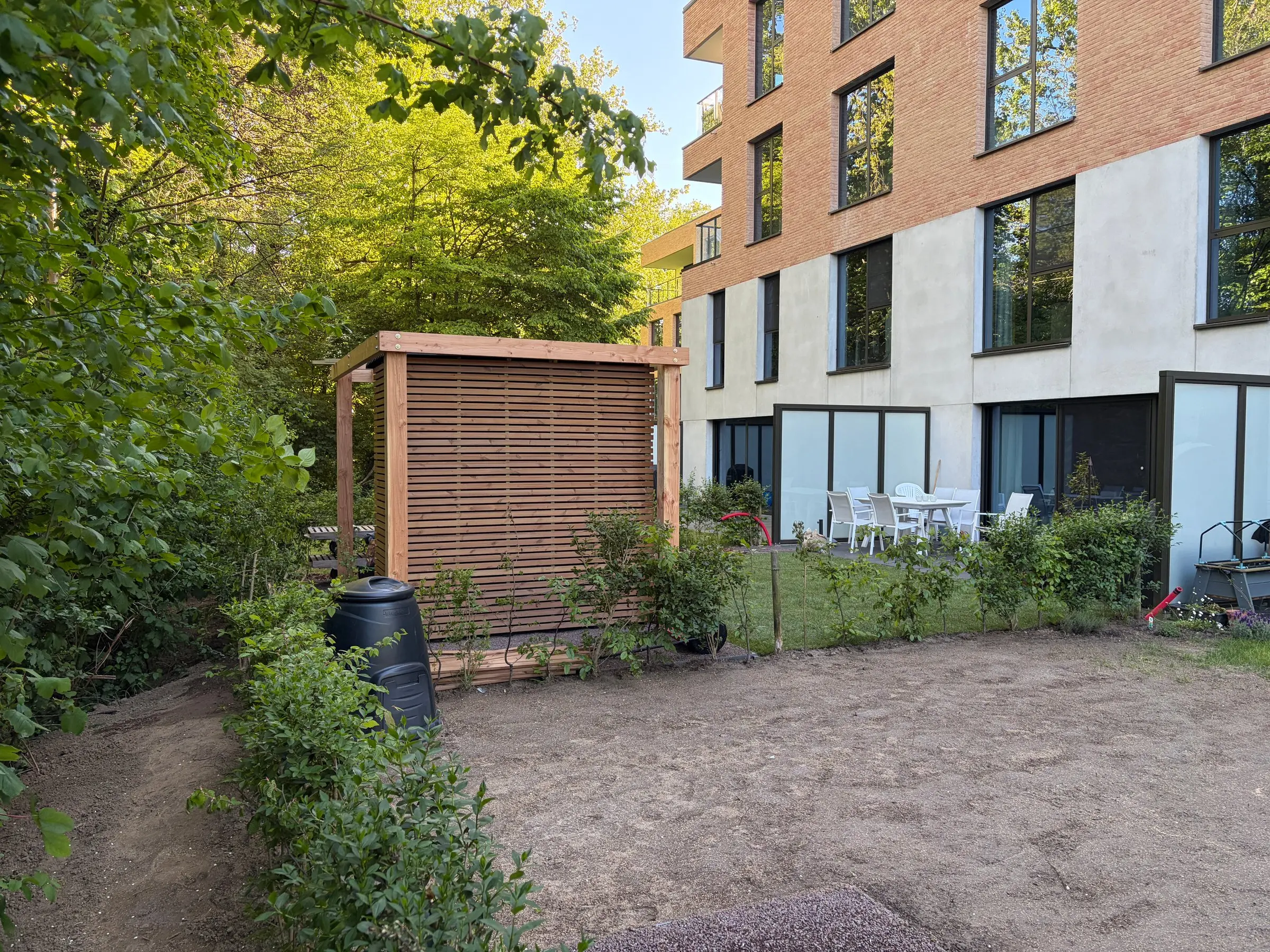 Afgewerkt tuinhuis met kale zandvlakte voor de gebouwen