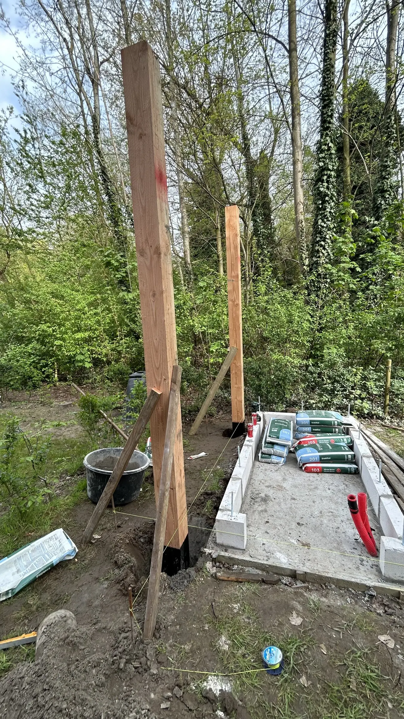 Eerste houten palen op stalen voeten naast de fundering