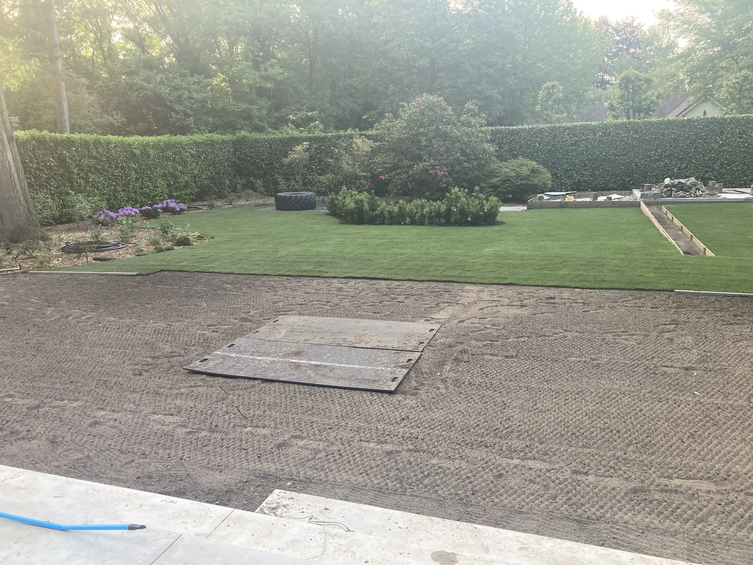 Voorbereide grond voor het gazon met de afgewerkte tuin erachter