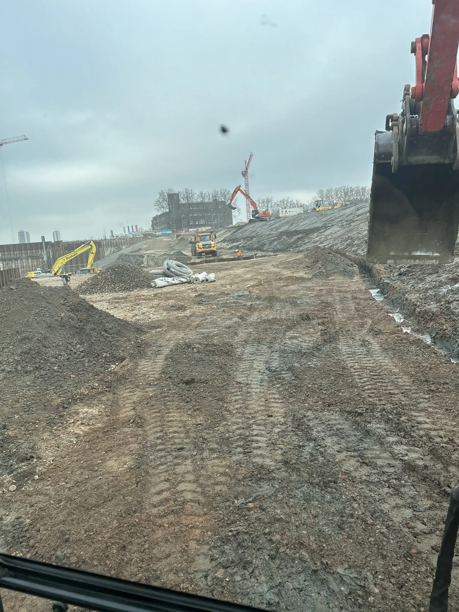 Zicht vanuit de cabine op de werf met sporen van zwaar materieel